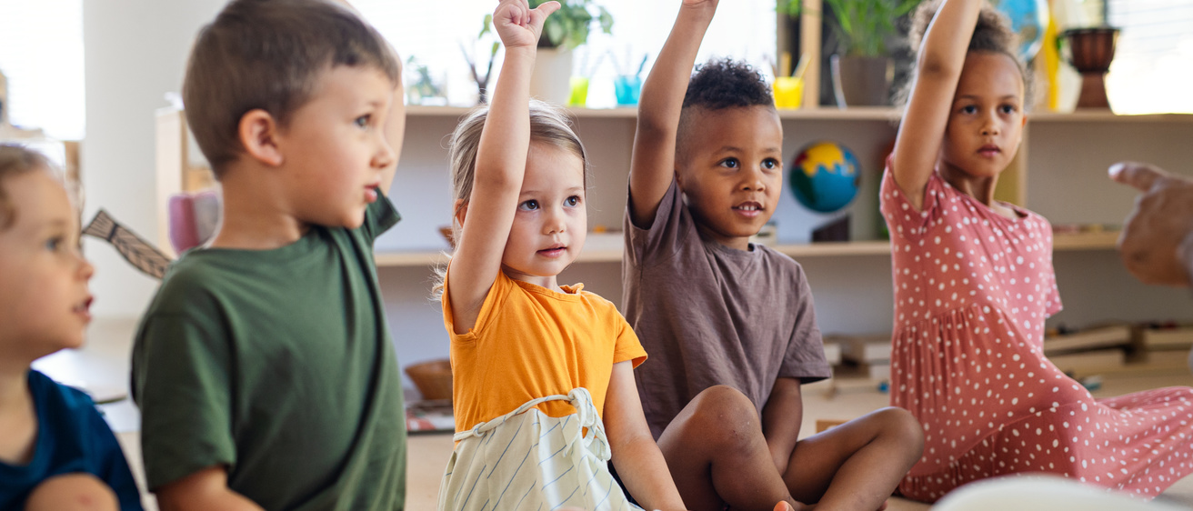 Stock photo of children raising their hands in a classroom